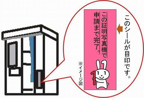 イラスト：証明写真機に「この証明写真機で申請まで申請まで完了」のシールが貼ってある。このシールが目印です。